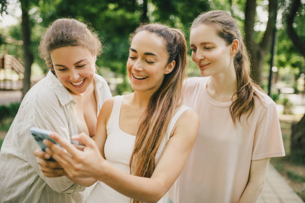istock Diverse millennial women spending time together in a park, using smartphone. 1574254914