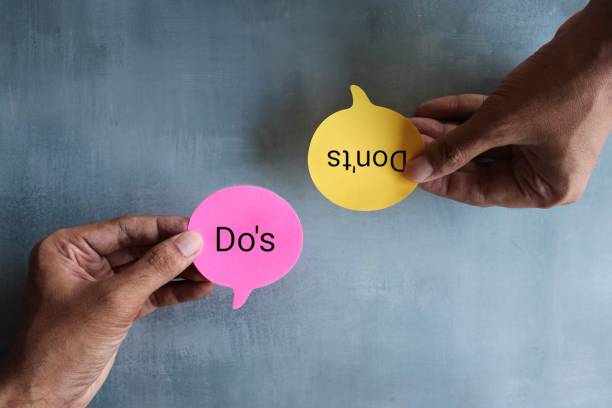 Hand holding speech bubble with text DO'S and DON'TS. Top view image of hand holding speech bubble with text DO'S and DON'TS. rules quotes stock pictures, royalty-free photos & images