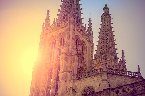 Gothic towers of the cathedral of Burgos with the orange sunset sun backlit forming a beautiful postcard