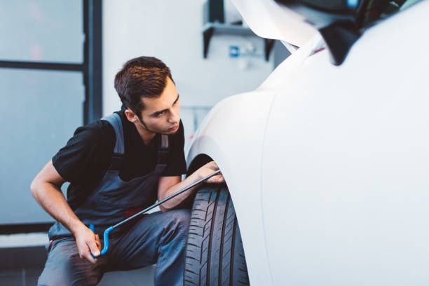 istock Car mechanic working to remove dent in workshop. 1574259190