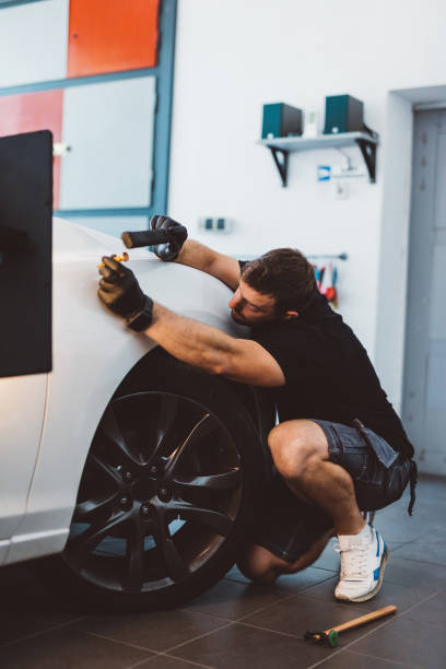 istock Car mechanic working to remove dent in workshop. 1574259229