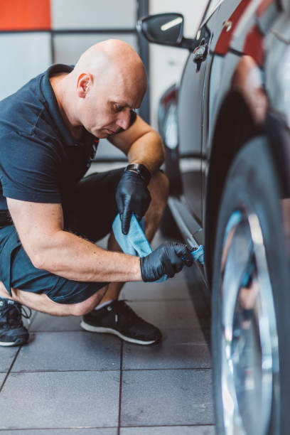 istock Service man washing car before detailing in workshop. 1574259310