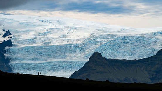 Nice view over Breiðamerkurjökull glacier, two tiny silhouettes standing in front, Jökulsárlón, Iceland