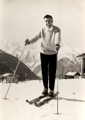 Vintage black and white photograph of a handsome and stylish man on the ski slopes of an alpine resort in the late 1950's.