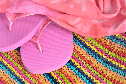 Bright pink sandals, sarong and striped raffia beach bag