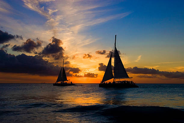 beau coucher de soleil avec voiliers - sailing sailboat sunset aruba photos et images de collection