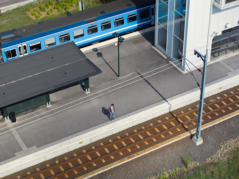 Aerial view of a person standing at a station platform and waiting for a train.