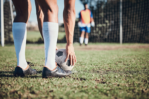Soccer ball, sports and feet of person to kick on field, fitness training or shoot for a goal in the net. Football, player and legs of athlete in exercise, competition or sport challenge for goals