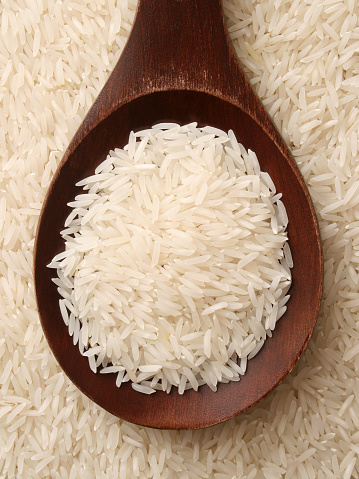 Top view of wooden spoon full of basmati rice