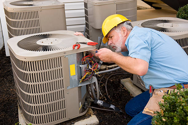 Mature Repairman Works On Apartment Air Conditioning Unit  air conditioner stock pictures, royalty-free photos & images