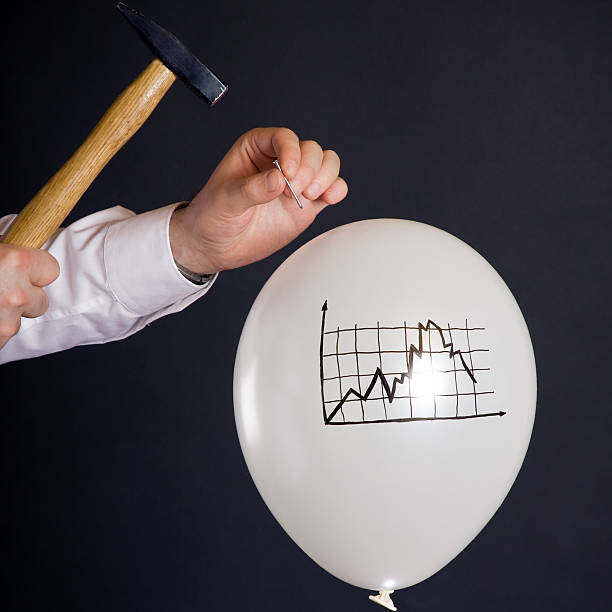 bursting the financial bubble businessman hitting a nail into a white balloon with a decaying financial chart hit the nail on the head stock pictures, royalty-free photos & images