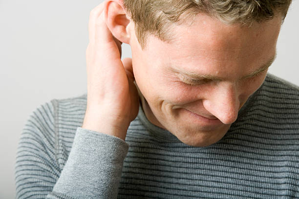 Portrait of a man scratching ear while looking away stock photo