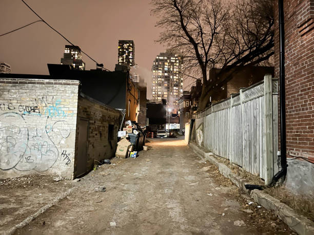 Dark and dirty alley of rubbish with graffiti on the wall in a suburb on the outskirts of Toronto. Ontario, Canada.