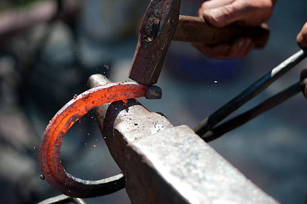 A man striking a red hot horseshoe on the anvil red hot horseshoe on the anvil blacksmith shop photos stock pictures, royalty-free photos & images