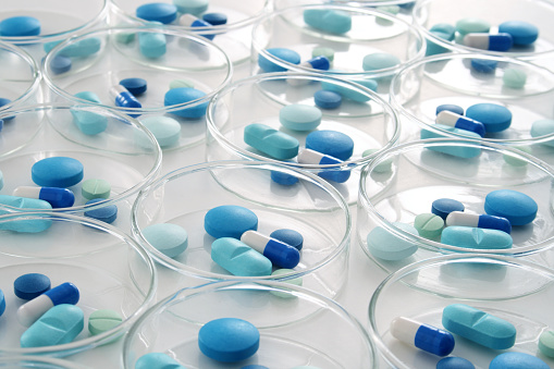 Groups of blue pills inside petri dishes