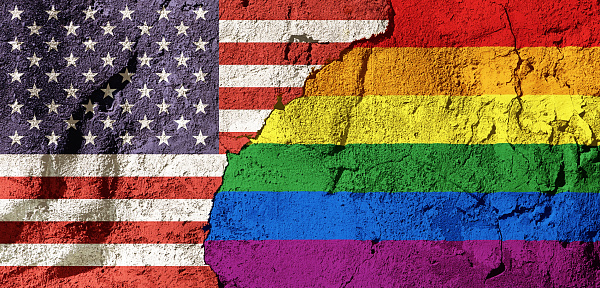 Acceptance or friction? National flag of the United States and the Gay Pride rainbow flag on a cracked, textured plastered wall.