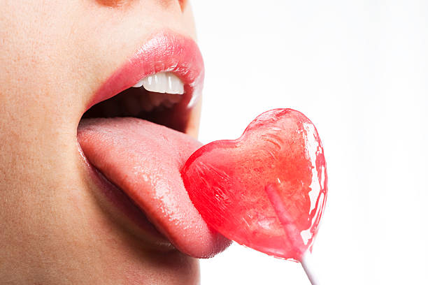 Girl licks heart lollipop  candy in mouth stock pictures, royalty-free photos & images