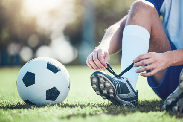 Ball, man and soccer player tie shoes for training, fitness games and performance on field. Closeup, football athlete and lace sneakers on feet, grass pitch and sports competition on stadium ground pelota, hombre y jugador de fútbol atan zapatos para entrenamiento, juegos de fitness y rendimiento en el campo. primer plano, atleta de fútbol y zapatillas de encaje en los pies, campo de césped y competición deportiva en el terreno del estadio