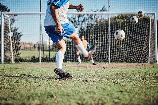 Sports, training and football player score a goal for challenge at a game or match at tournament. Fitness, exercise and back of soccer athlete kicking a ball at practice on outdoor field at stadium.