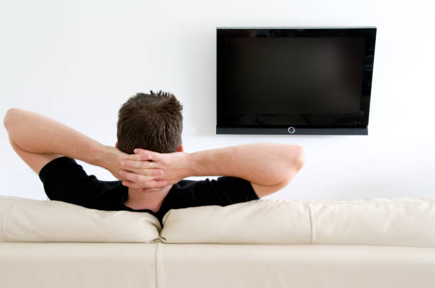 istock Man relaxes in sofa and watches tv on flatscreen 157429955
