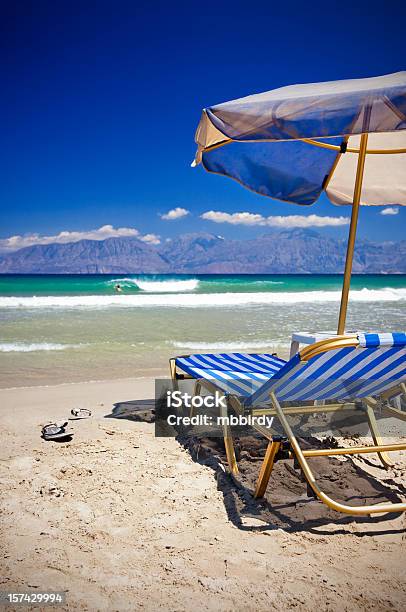 Foto de Sol Cadeiras E Guardachuva Na Praia e mais fotos de stock de Creta - Creta, Praia, Sombrinha de praia