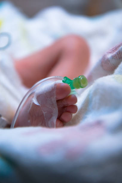 Closeup foot of baby with newborn ankle tag on bed in hospital textured background