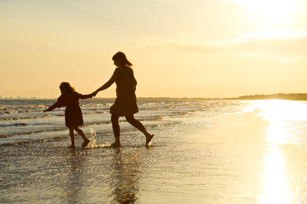 istock Mother and Daughter on beach silhouette 157430252