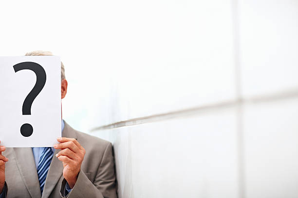 Portrait Of Confident Businessman Holding Book While Sitting Against Wall