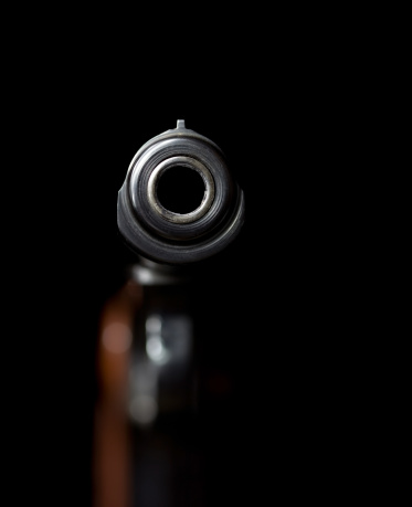 Handgun on black illuminated by one small light, possibly a streetlight or moonlight metaphor.