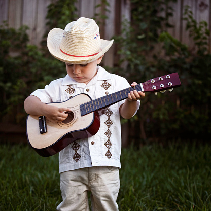 a liitle 3 years old boy dress like a traditional cuban folk music guitar player