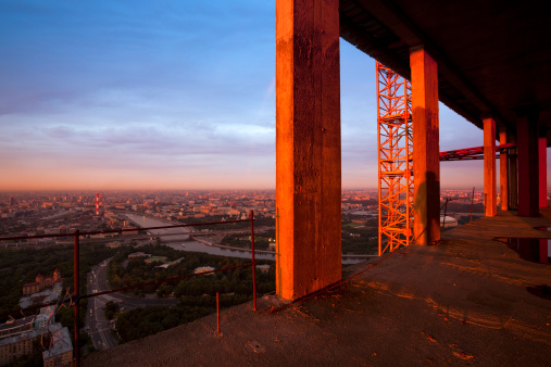 Moscow skyline with river, roads, bridge. Construction frame in sunset light. There are shadow of a man on one column