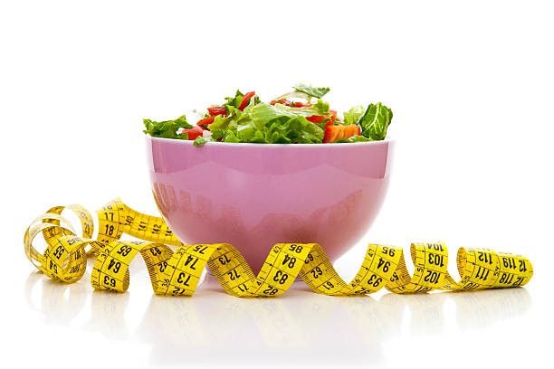 Salad in bowl by tape measure, on white background
