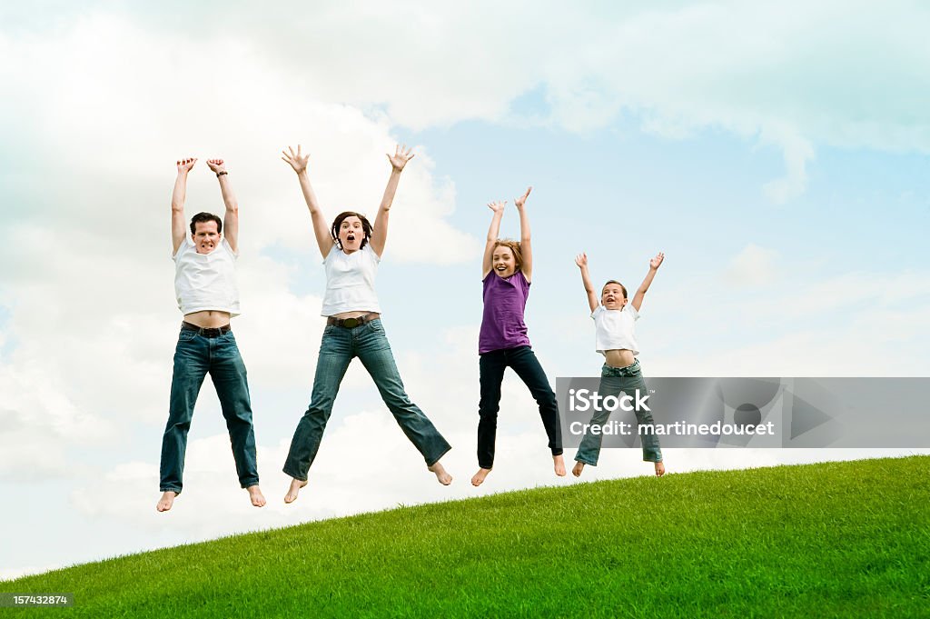 Família feliz de quatro pulando na Terra, comprimento. - Foto de stock de Adulto royalty-free