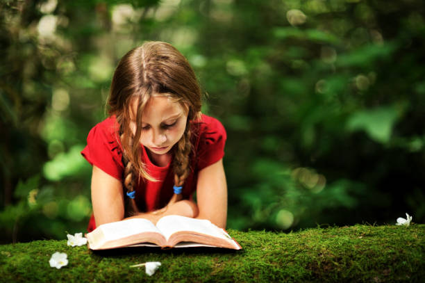 Young girl reading her bible in nature