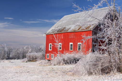 Red barn surrounded by ice in the Pioneer Valley of Massachusetts. Photo taken after a historic winter ice storm entombing everything in the landscape with a thick glaze of ice. The Pioneer Valley is known for its scenery and as a vacation destination