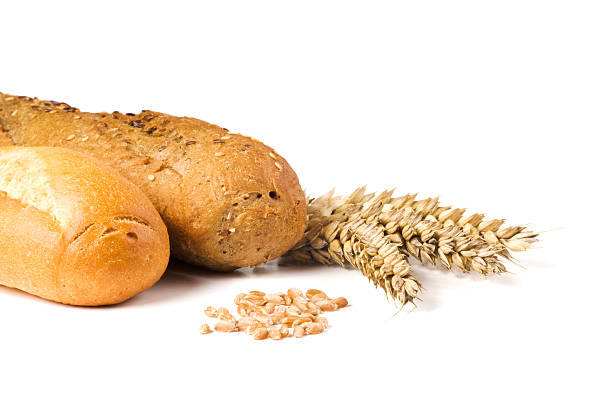 Baguettes and ripe golden wheat with seeds on white background with dropped shadow. Close-up, side view.