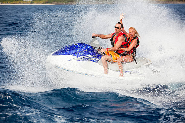 Energetic adult couple riding wave runner stock photo