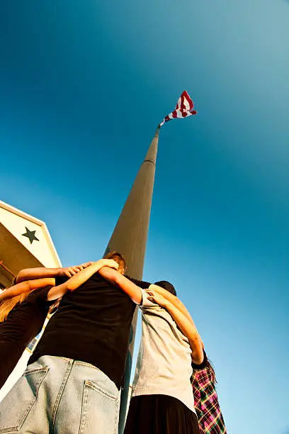 Photo of Teenagers Praying Around a Flag Pole