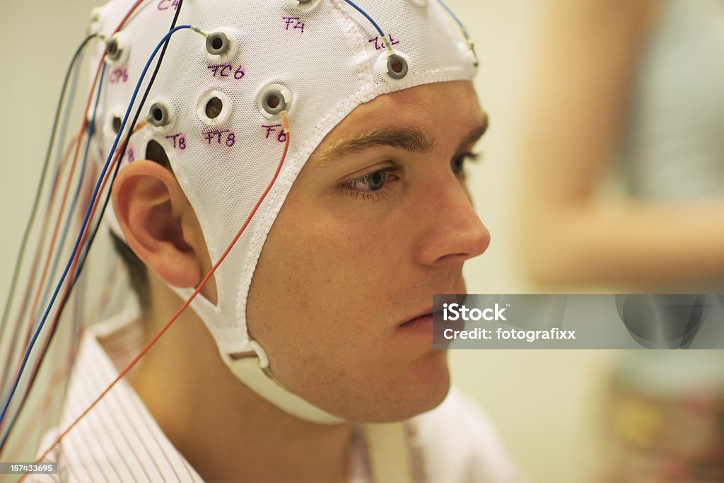 man connected with cables to computer - EEG for resarch for a scientific experiment, a young man is connected with cables to a computer, EEG for research EEG Stock Photo