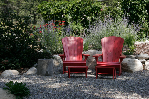 Country Garden setting.  In the cool of a sun dappled afternoon in the garden. Red flowers in the background are Minardas. Chairs are recycled material, hence the texture. 