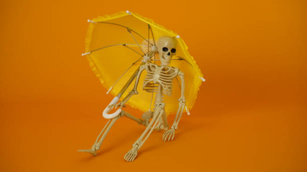 istock A skeleton sitting under a yellow umbrella. 1574338532