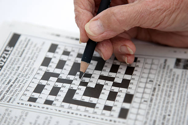 istock Woman's hand starting to write on crossword 157434368