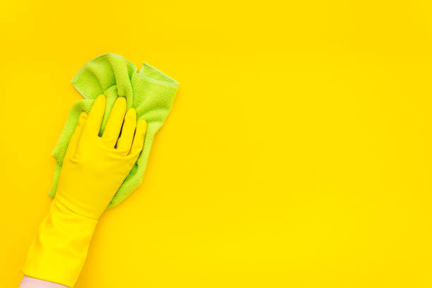 istock Female cleaner hand in yellow glove cleaning surface with duster 1574344923
