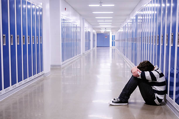 chico deprimido en el pasillo de la escuela - acoso escolar fotografías e imágenes de stock