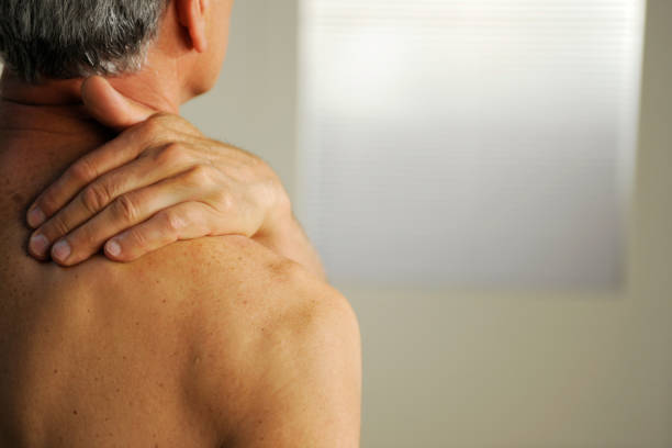 A close-up image of a woman’s hand massaging her bare shoulder and neck , set against a bright yellow background. The photo represents themes of self-care, relaxation, pain relief, and wellness, emphasizing a healthy and balanced lifestyle.