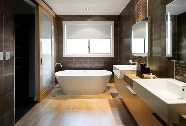 Luxurious Bathroom Australian Luxury bathroom with brown tiles and hardwood floor, focusing on a free standing bath. Clipping path around the windows and reflections in mirror/door. free standing bath stock pictures, royalty-free photos & images