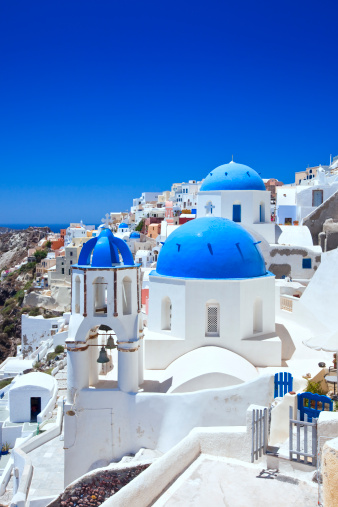 traditional greek village Oia of Santorini, with blue domes of churches in sunset light, Greece, wide panorama, toned