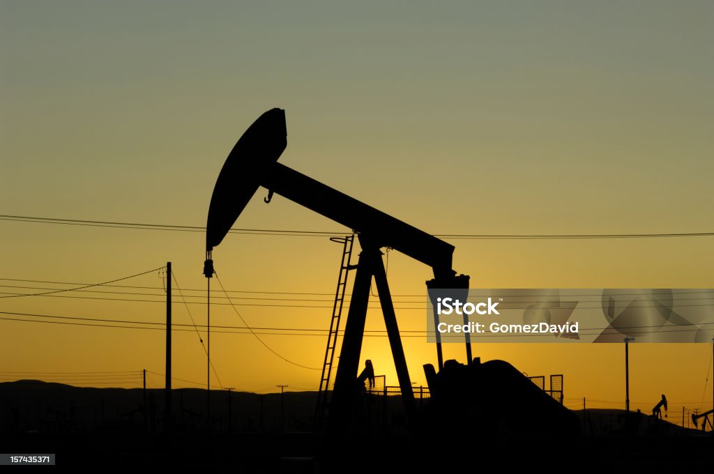 Olio Pumpjack contro un cielo al tramonto - Foto stock royalty-free di Ambientazione esterna