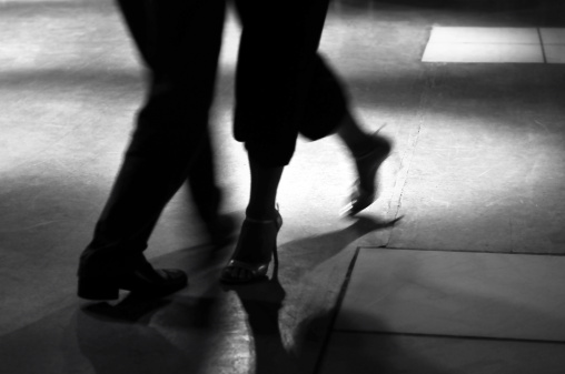 Couple tangoing in a ballroom. Captured in black and white with motion blur.