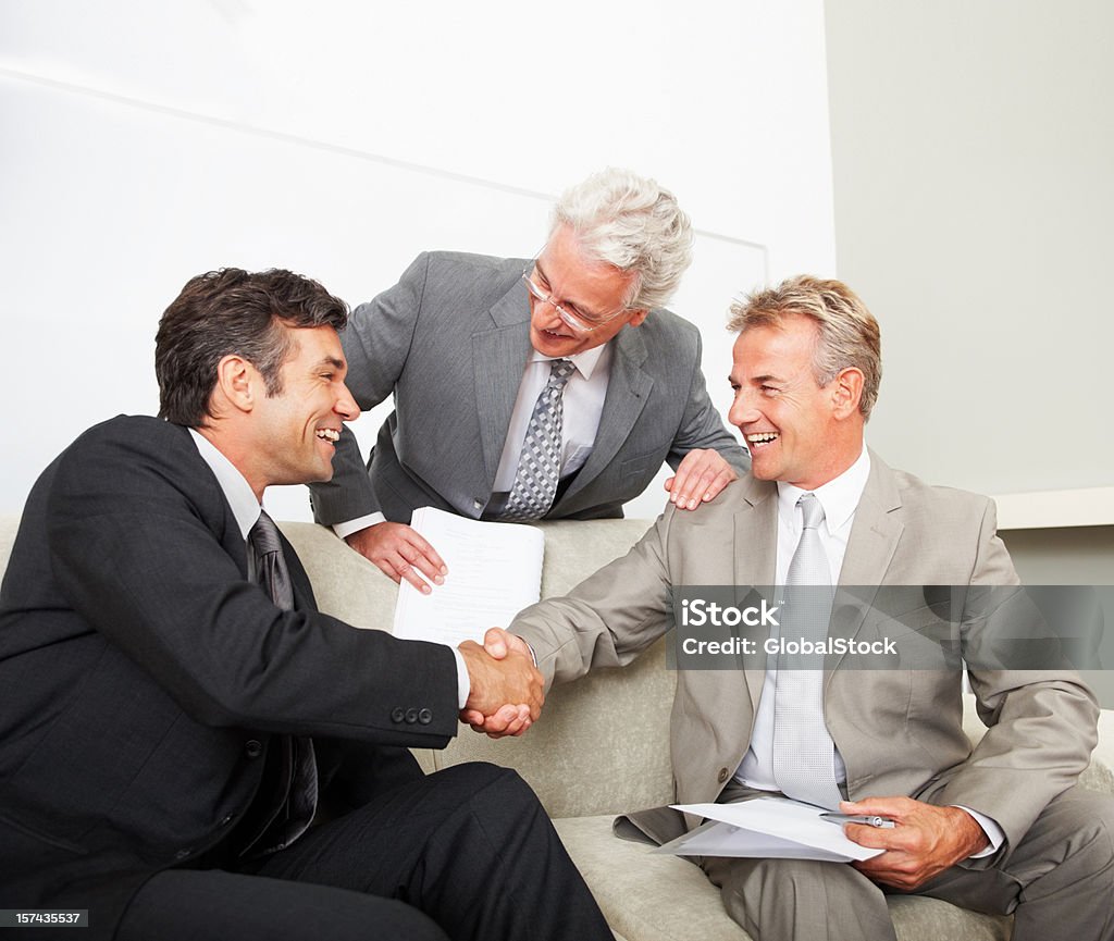 Colleghi di lavoro stringe la mano in ufficio - Foto stock royalty-free di 45-49 anni